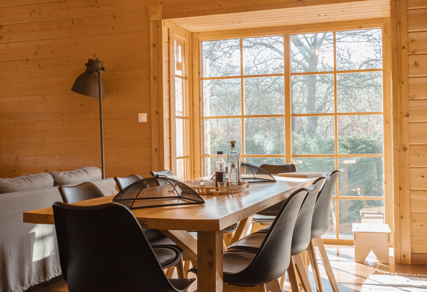 Dining area beside a tall picture window looking onto the forest