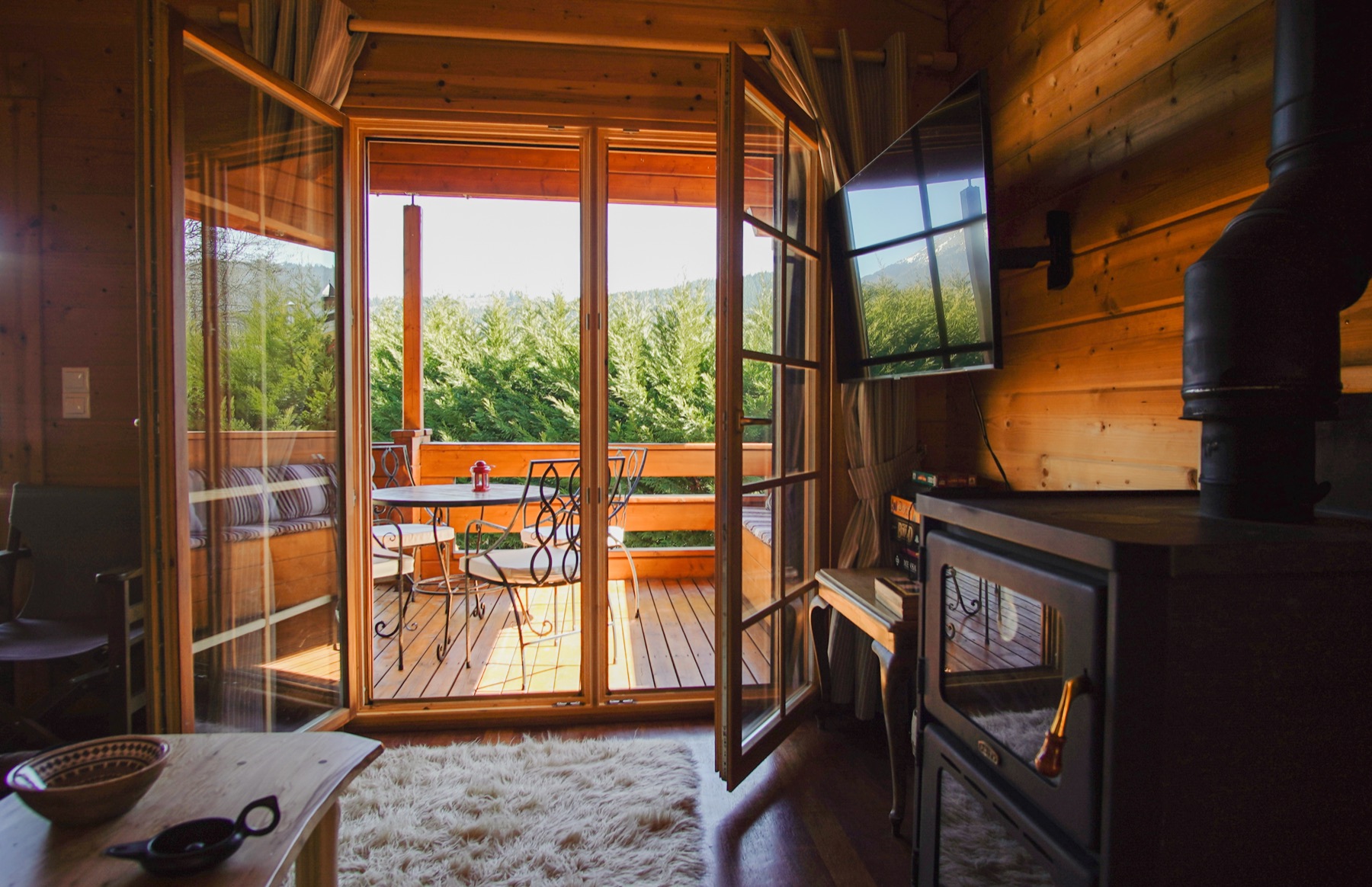 Living room with wood-burning fireplace at the Karpenisi forest chalet, opening onto the balcony
